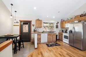 Eine moderne Küche mit Holzausbau, einem Edelstahlkühlschrank und einem Essbereich mit einer Bank und Stühlen.