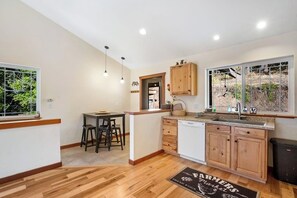 A modern kitchen with wooden cabinets, a dining area, and a view of the outdoors. - Custom 3BR - Balcony - Washer Dryer (Ronald)