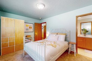 Ein Schlafzimmer mit einem Bett, einem Kleiderschrank, einem Spiegel und einem kleinen Hocker.
