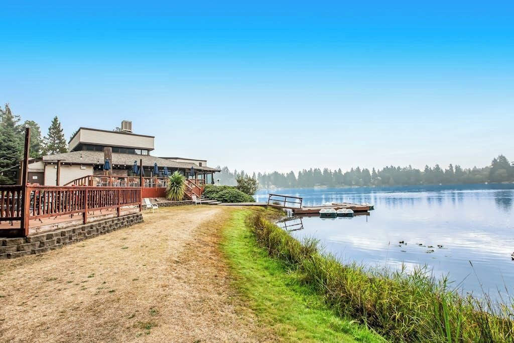 A lakeside property with a wooden deck, a dock, and a building with a flat roof.