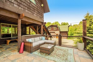 A wooden deck with a sofa, wicker furniture, and a patterned rug. - Quiet 2BR riverfront cabin with wood stove (Cle Elum)