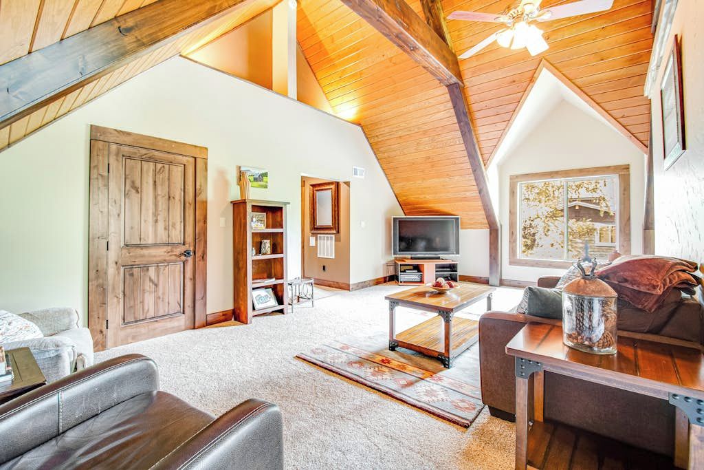 Un loft spacieux avec un plafond haut, une grande porte en bois, un téléviseur et un coin salon confortable avec une table basse.