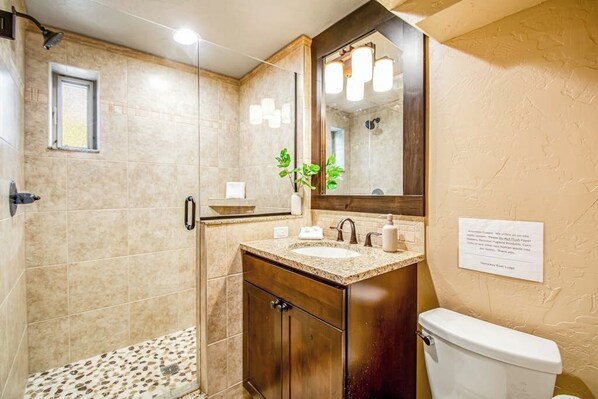 Ein Badezimmer mit Dusche, Waschbecken, Toilette und Spiegel.