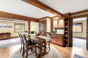 A dining area with a wooden table and chairs, a kitchen with wooden cabinets, and a view of the outdoors. - Quiet 2BR riverfront cabin with wood stove (Cle Elum)
