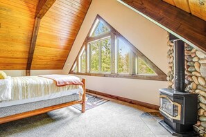 Een slaapkamer met een bed, een stenen open haard en een groot raam.