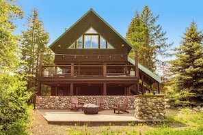 A two-story log cabin with a stone wall and outdoor seating area. - Quiet 2BR riverfront cabin with wood stove (Cle Elum)