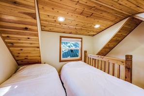 A bedroom with two beds, wooden ceiling, and a window with a view. - 2BR lakefront cabin with private dock (Cle Elum)