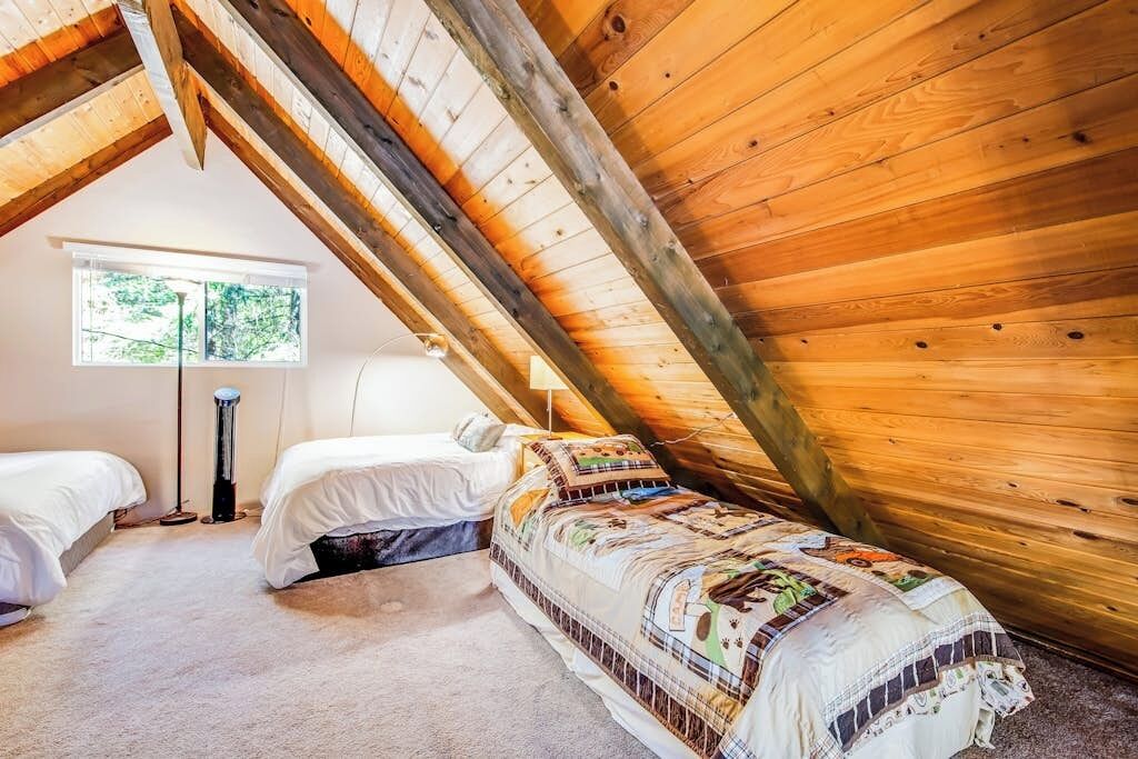 Une chambre avec deux lits, une fenêtre et un plafond en pente.
