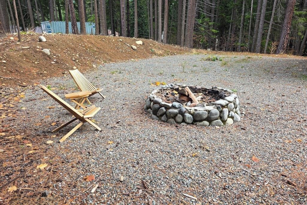 Ett område med grus, en eldstad och en trästol.