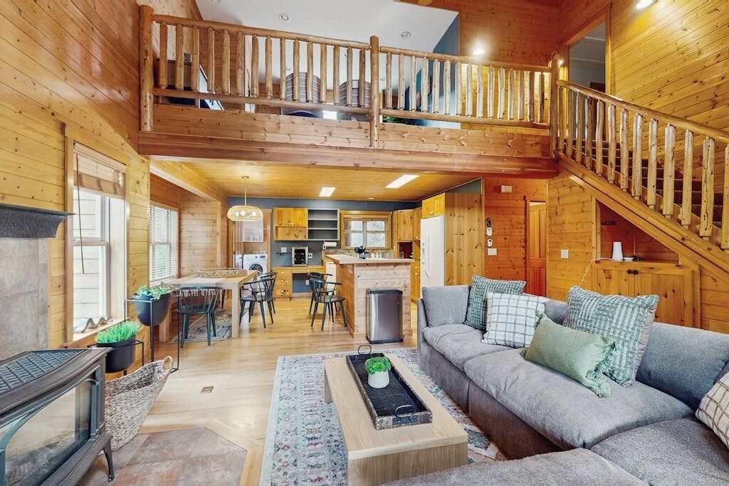 A spacious wooden cabin with a loft bedroom, a dining area, and a kitchen.