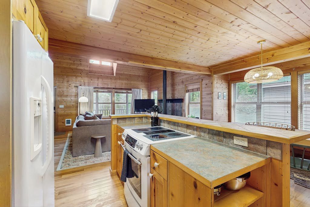 A wooden cabin interior with a kitchen, dining area, and living room.