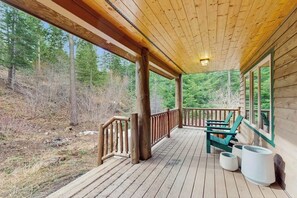A wooden deck with a railing, outdoor seating, and a view of a forested area. - 3BR Cabin, dog-friendly with fireplace and views (Cle Elum)