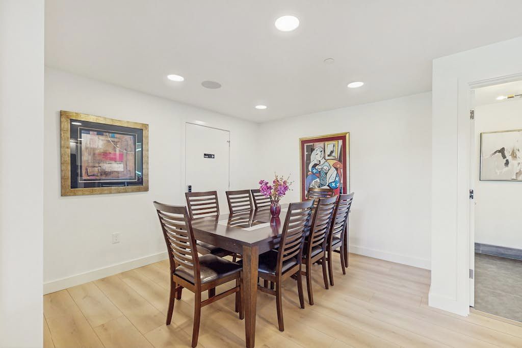 Un espace repas avec une table et des chaises en bois, entouré de murs blancs et doté d’un plancher en bois.
