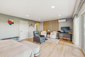 Una habitación de hotel moderna con cama, zona de estar, televisión y una puerta.