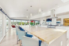 Eine moderne Küche mit einer großen Kochinsel, Barhocker und Blick auf Grünflächen.