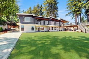 Een modern huis met twee verdiepingen, een overdekt terras en een verzorgd gazon.