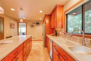 A kitchen with wooden cabinets, a double sink, and a refrigerator. - Large 4BR Bayview Dog Friendly - Deck - Firepit (Gig Harbor)