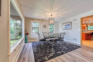 A dining area with a table and chairs, a chandelier, and artwork on the walls. - Large 4BR Bayview Dog Friendly - Deck - Firepit (Gig Harbor)