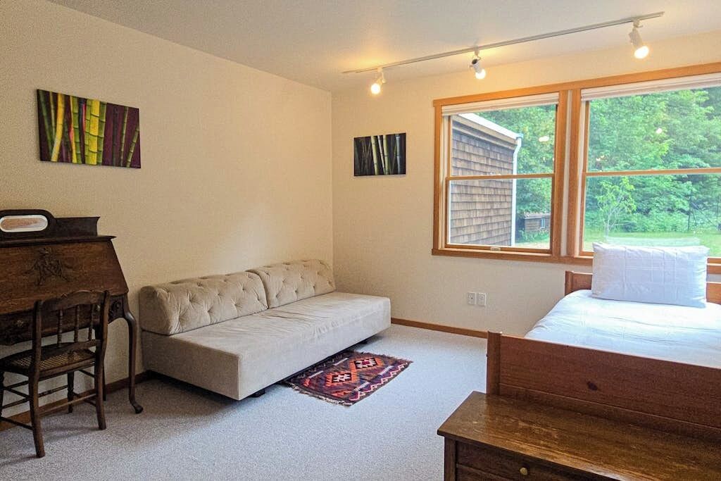 Een slaapkamer met een bed, een bank, een bureau en een raam.