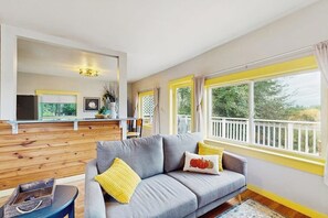 A modern living room with a grey sofa, yellow cushions, and a view of a balcony.