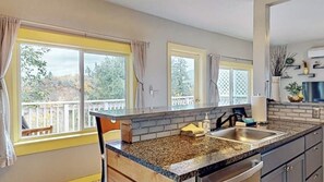 Una cocina con encimeras de granito, un lavabo doble y vistas al exterior.