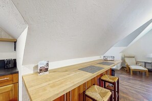 A kitchen with a wooden countertop, bar stools, a chair, and a kettle. - 0BR Studio on lush grounds with nearby horses (Bainbridge Island)