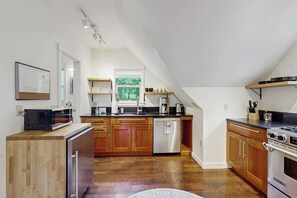Une cuisine moderne avec des meubles en bois, des appareils électroménagers en acier inoxydable et une vue sur l’extérieur.