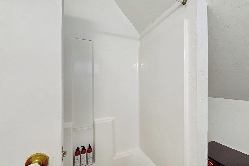 A white door with a brass doorknob and a small set of red and white bottles on a white surface.