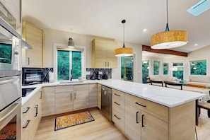 A modern kitchen with a large island, built-in appliances, and pendant lighting. - 4BR Home with bright open living (Bainbridge Island)