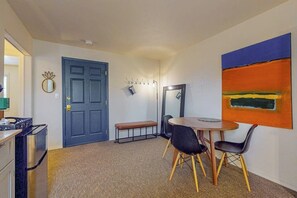 Ein Zimmer mit einem runden Tisch, zwei Stühlen, einer Bank, einer Tür und einer Wandleuchte.
