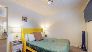 Ett sovrum med en säng, sänglampor, en platt-TV och en takfläkt.