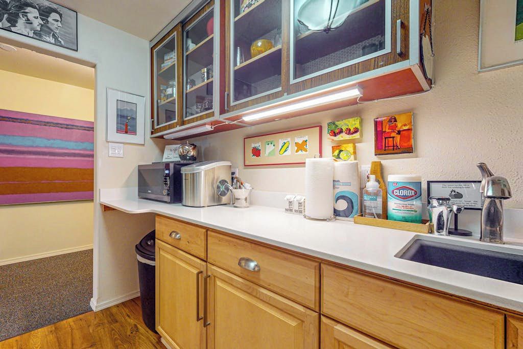 A kitchen with wooden cabinets, a microwave, a sink, and various kitchen items.