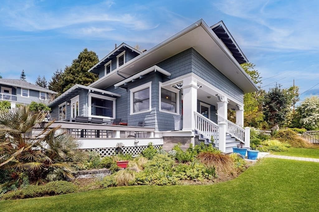 A two-story house with a front porch, a covered entryway, and a well-maintained garden.