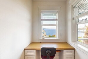 A corner room with a desk, a chair, and a window with a view of the sea. - Waterfront house with beach access (Kingston)