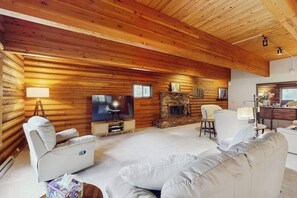 Ein rustikales Holzhaus-Interieur mit Kamin, Fernseher und einer gemütlichen Sitzecke.
