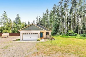 A single-story house with a garage, surrounded by a forested area.