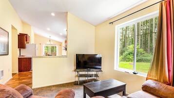 A living room with a television, sofa, and a window with curtains.