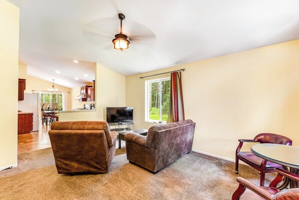 A living room with a sofa, armchair, and a dining table with chairs.