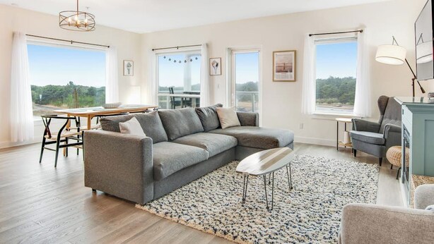 Een moderne woonkamer met een hoekbank, een eettafel en uitzicht op het groen.