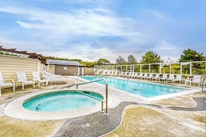 Une piscine avec des chaises longues, un jacuzzi et un espace abrité agrémenté d’une pergola.