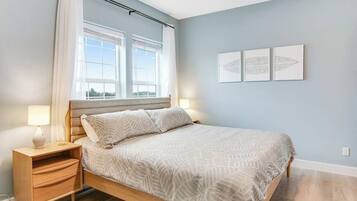 Un dormitorio con una cama, mesita de noche, lámpara y tres cuadros en la pared.