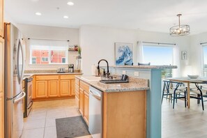A modern kitchen with wooden cabinets, a granite countertop, and a built-in island with a sink. - Oceanfront 2BR 3rd-Floor | Balcony | Pool (Westport)