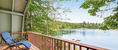 A wooden deck with a view of a lake, surrounded by trees.