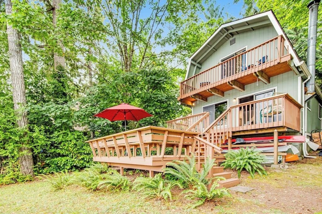 Une cabane en bois à deux étages, dotée d’un balcon et entourée d’une végétation luxuriante.