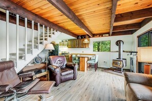 Ampla sala de estar com lareira, mobiliário em couro, escada e vista para o exterior.