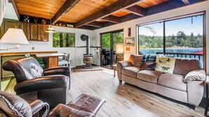 A spacious living area with a wooden ceiling, a sofa, a leather chair, and a fireplace. - 1BR Soundview Dog Friendly - Dock - WoodStove (Shelton)