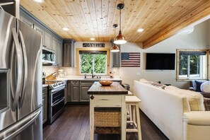 Une cuisine équipée d’appareils modernes, avec un plafond en bois et une vue sur l’extérieur.