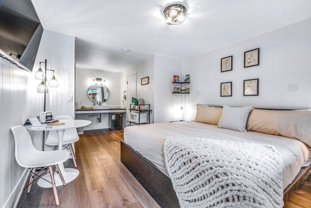 Une chambre moderne avec un grand lit, une table de chevet, un miroir et un petit bureau avec une chaise.