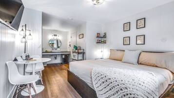 Un dormitorio moderno con una cama grande, una mesita de noche, un espejo y un escritorio pequeño con una silla.