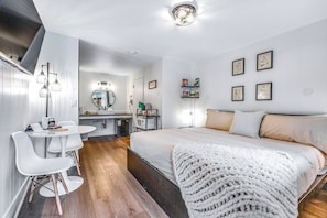 Une chambre moderne avec un grand lit, une table de chevet, un miroir et un petit bureau avec une chaise.
